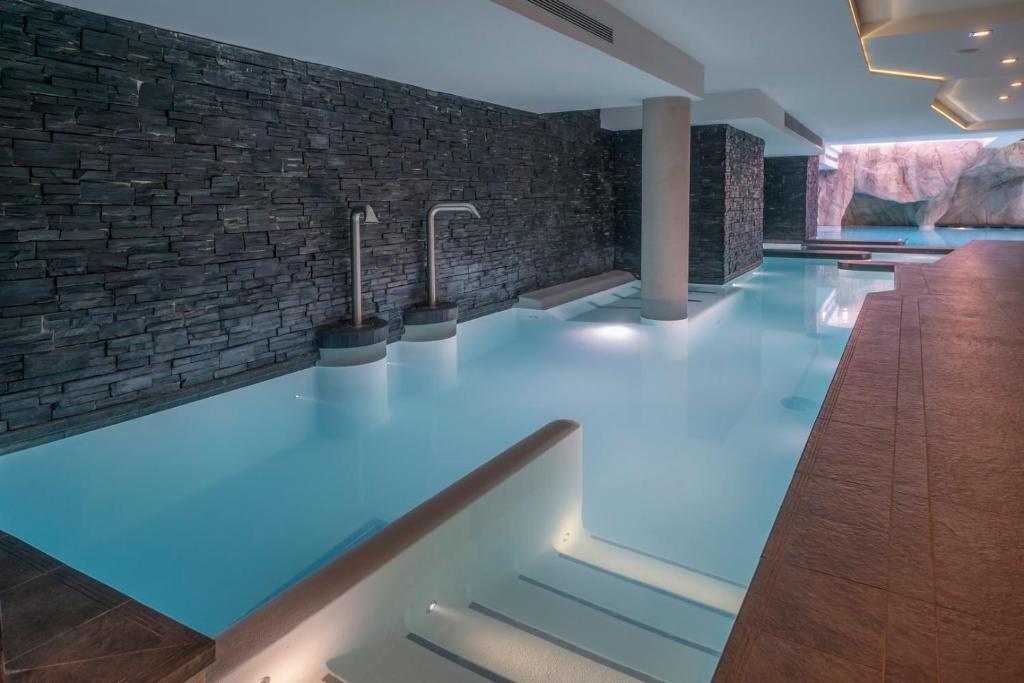 a swimming pool with blue lighting and a brick wall at Le Kaïla in Méribel