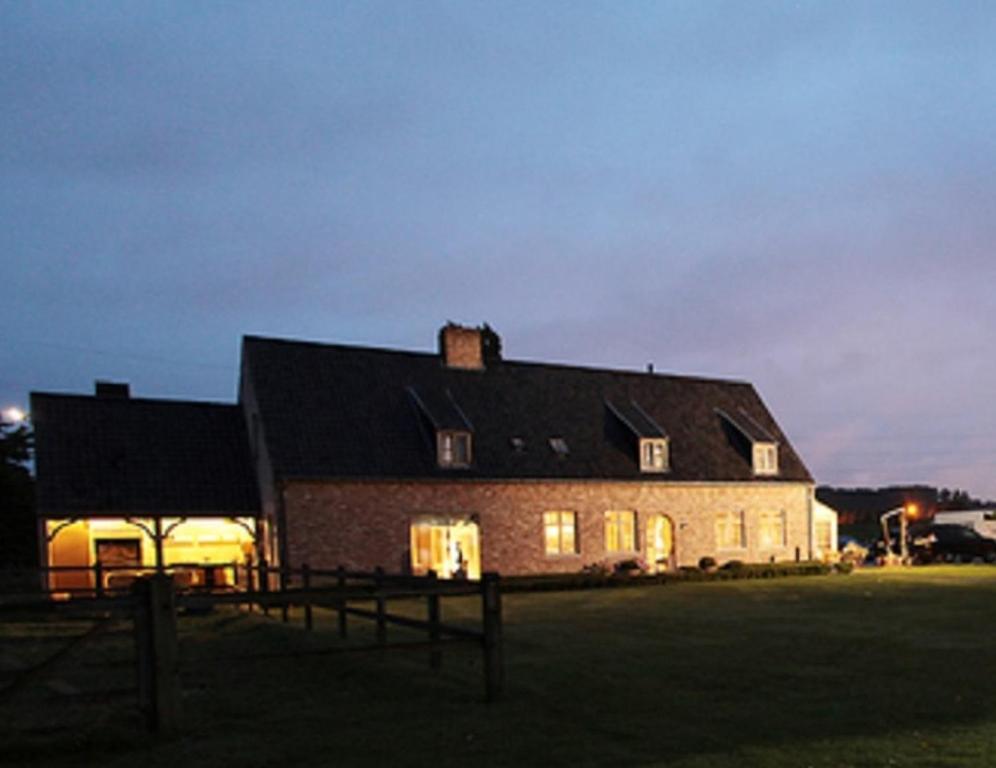 ein großes Backsteinhaus in der Nacht mit eingeschaltetem Licht in der Unterkunft B&B Goed Ten Hulle in Pittem