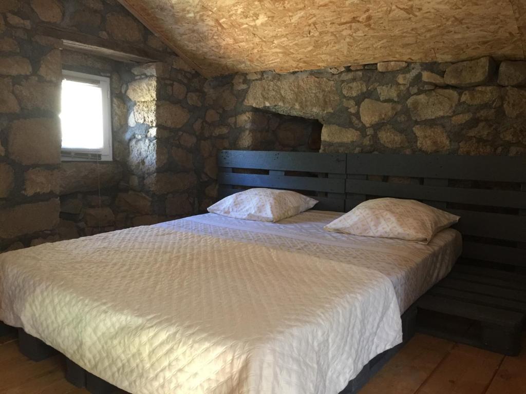 - une chambre avec un lit dans un mur en pierre dans l'établissement Casetta, à Olivese