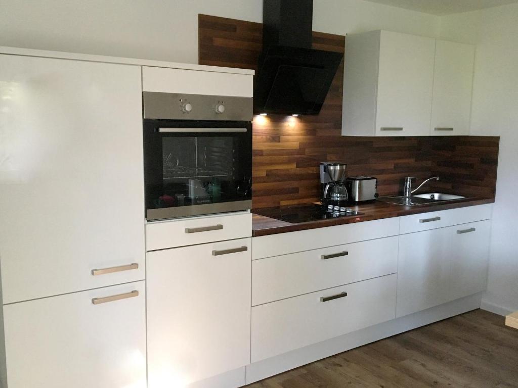 a kitchen with white cabinets and a stove top oven at Ferienwohnung Unsere Mühle in Kirchbach