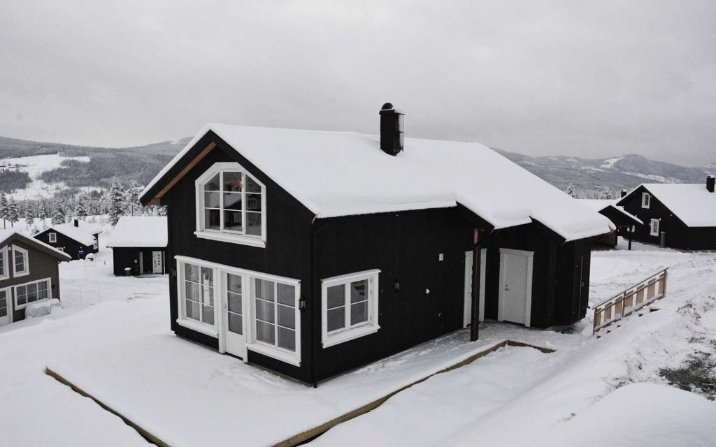 a black house with snow on top of it at Golfvegen 76 in Trysil