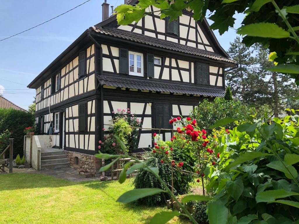 a black and white house with flowers in the yard at La Stube de Marinette 5 étoiles in Hipsheim