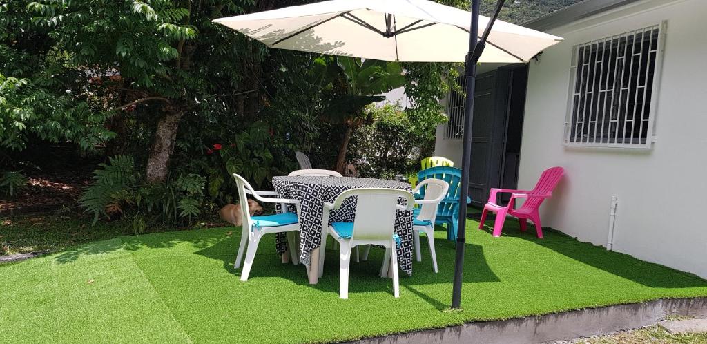 een tafel en stoelen op een gazon met een parasol bij Villa Azalées in Salazie