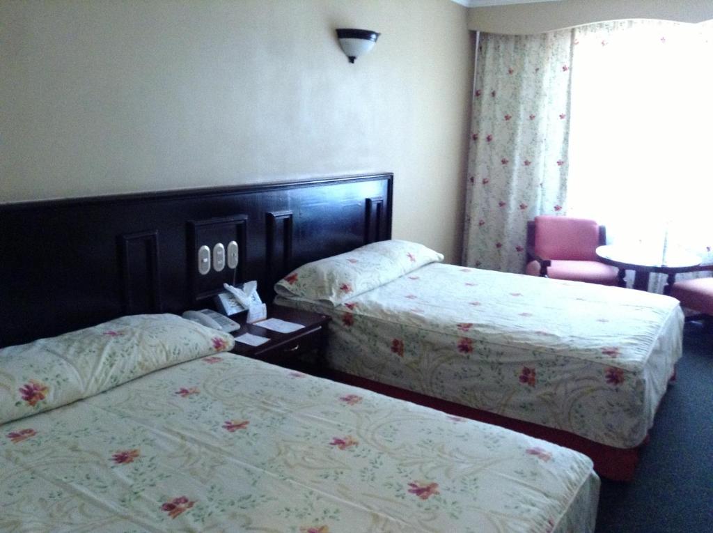 a hotel room with two beds and a table at Hotel Real de Uruapan in Uruapan del Progreso