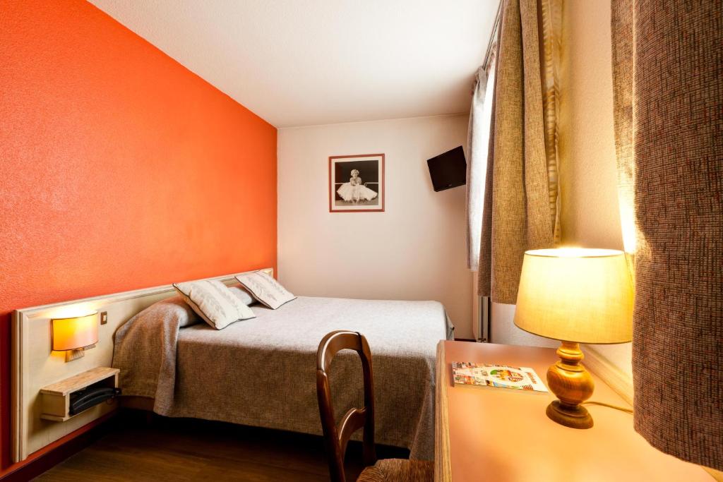 Habitación pequeña con cama con pared de color naranja en Hotel Le Lumière en Lyon