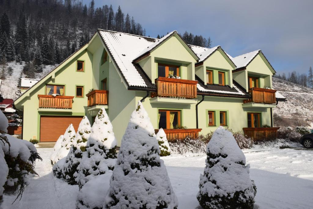 une maison recouverte de neige avec des arbres devant elle dans l'établissement Penzion Soltis, à Liptovské Revúce