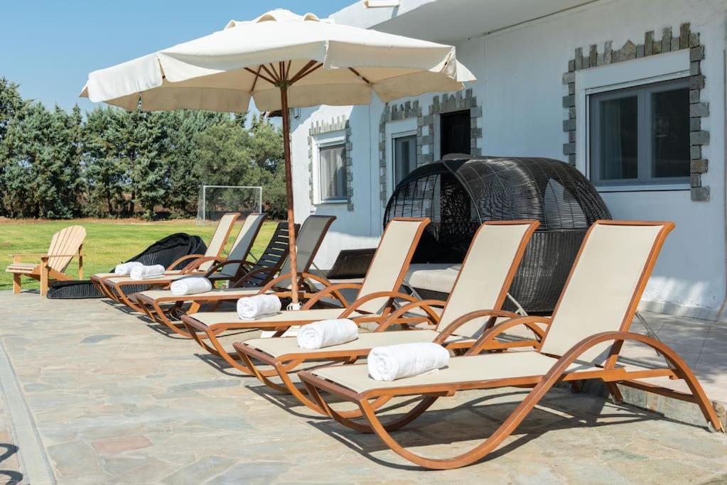 rząd krzeseł ogrodowych z parasolem w obiekcie Villa Hara w mieście Nea Iraklia
