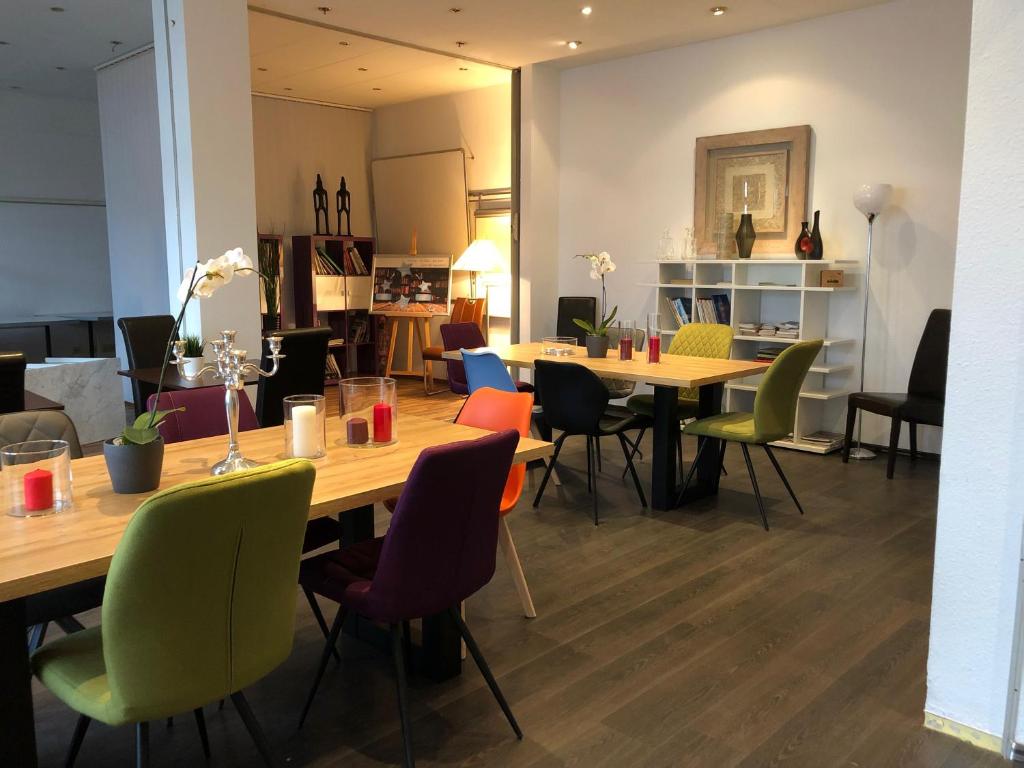 a dining room with wooden tables and colorful chairs at Stargaze Forum Hotel Düsseldorf-Hilden in Hilden