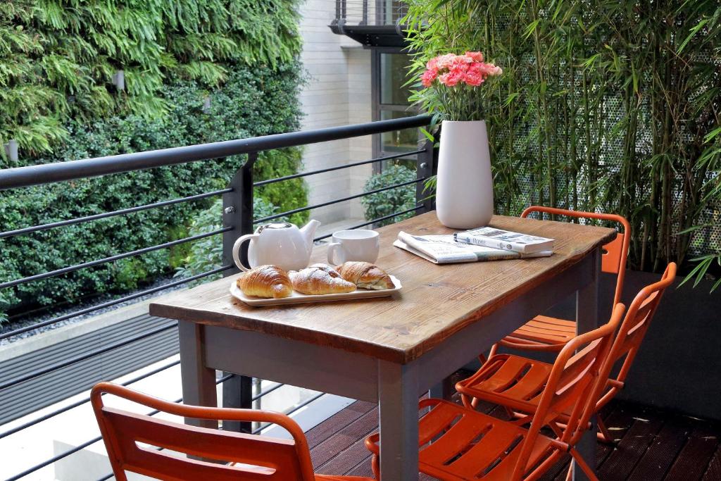 a wooden table with a tray of pastries on a balcony at Rome Unique Monti Colosseum in Rome