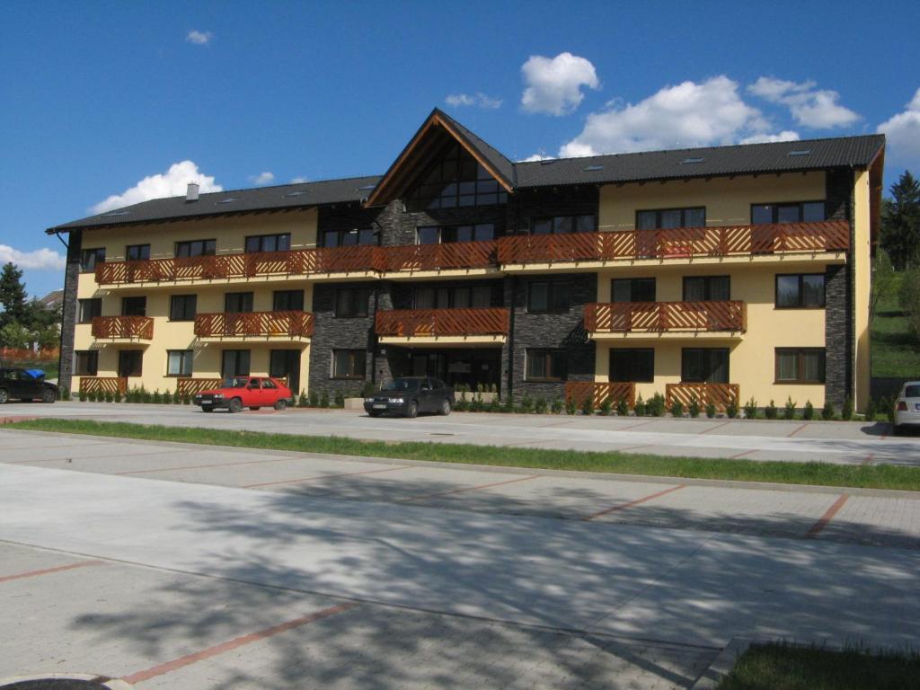 a large building with cars parked in front of it at Apartman pod Dedovkou in Oščadnica