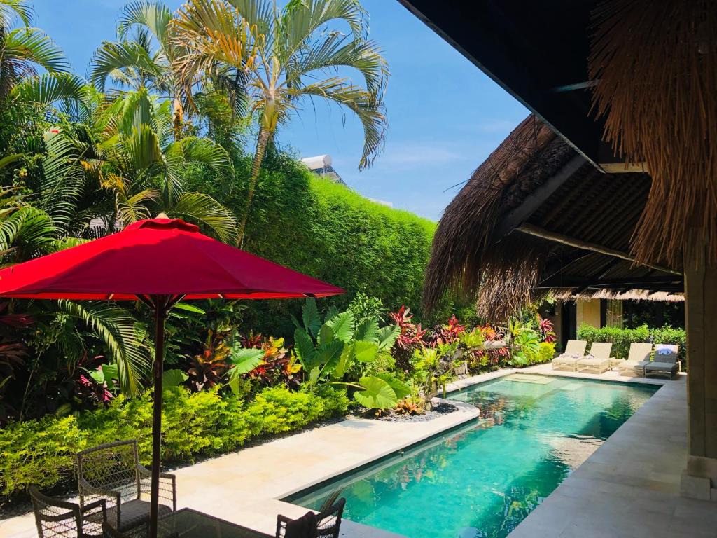 a red umbrella next to a swimming pool at Villa Elleo in Seminyak