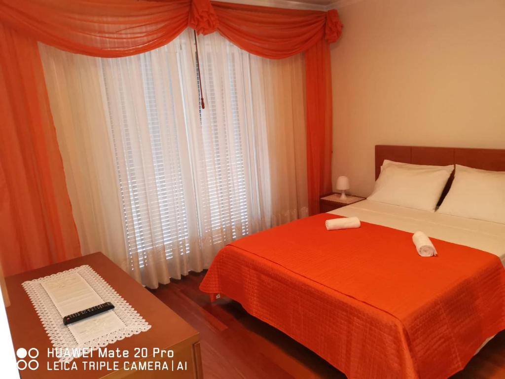 a bedroom with a bed and a red blanket and a window at Andrade Blue in Caniço