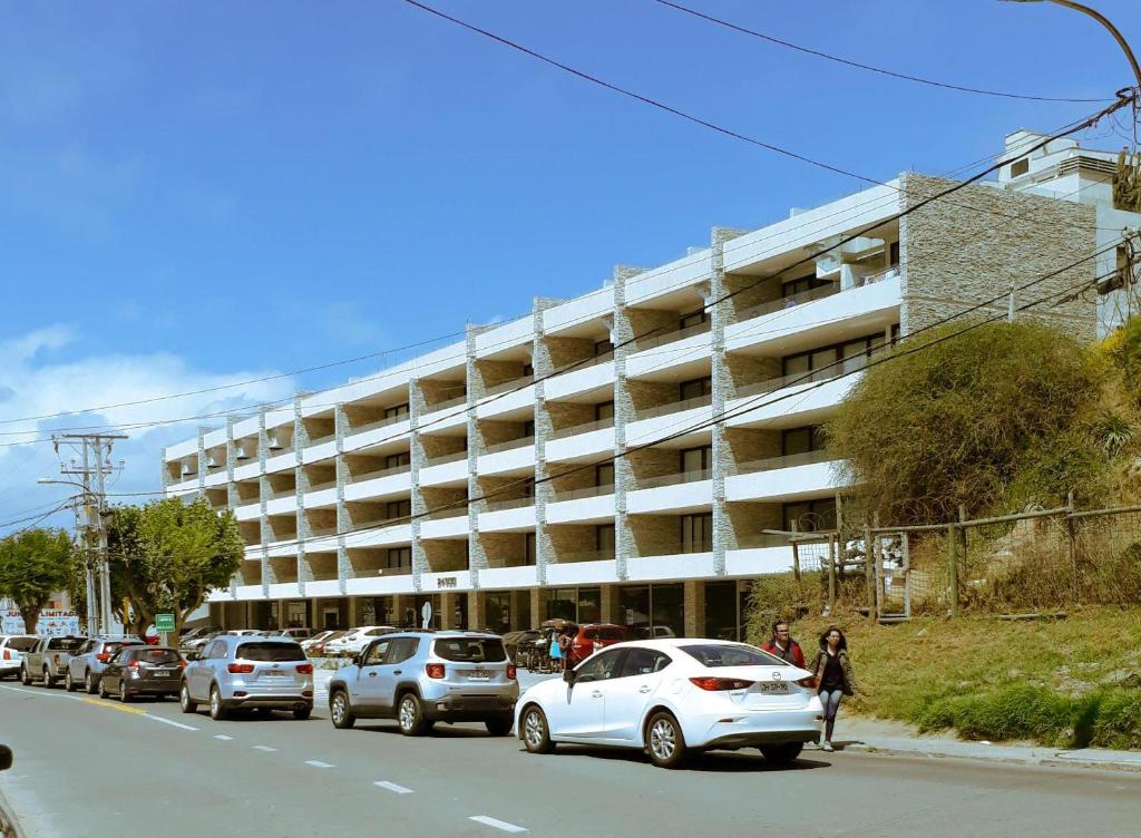 un estacionamiento con autos estacionados frente a un edificio en Concón, depto "Costa Borgoño" frente a playa La Boca, en Concón