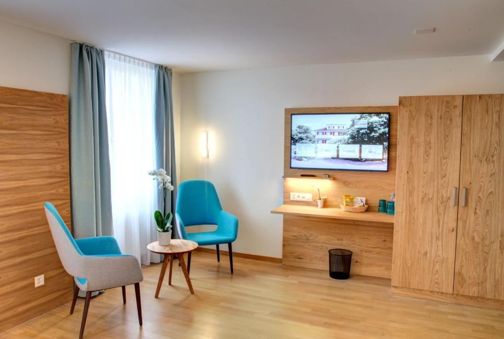 Habitación con 2 sillas azules y TV. en Hotel & Restaurant Hofmatt en Münchenstein