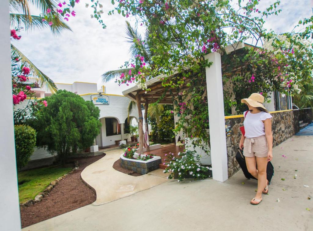 a woman standing in front of a flower garden at Hostal Sueños Silvestres in Puerto Ayora