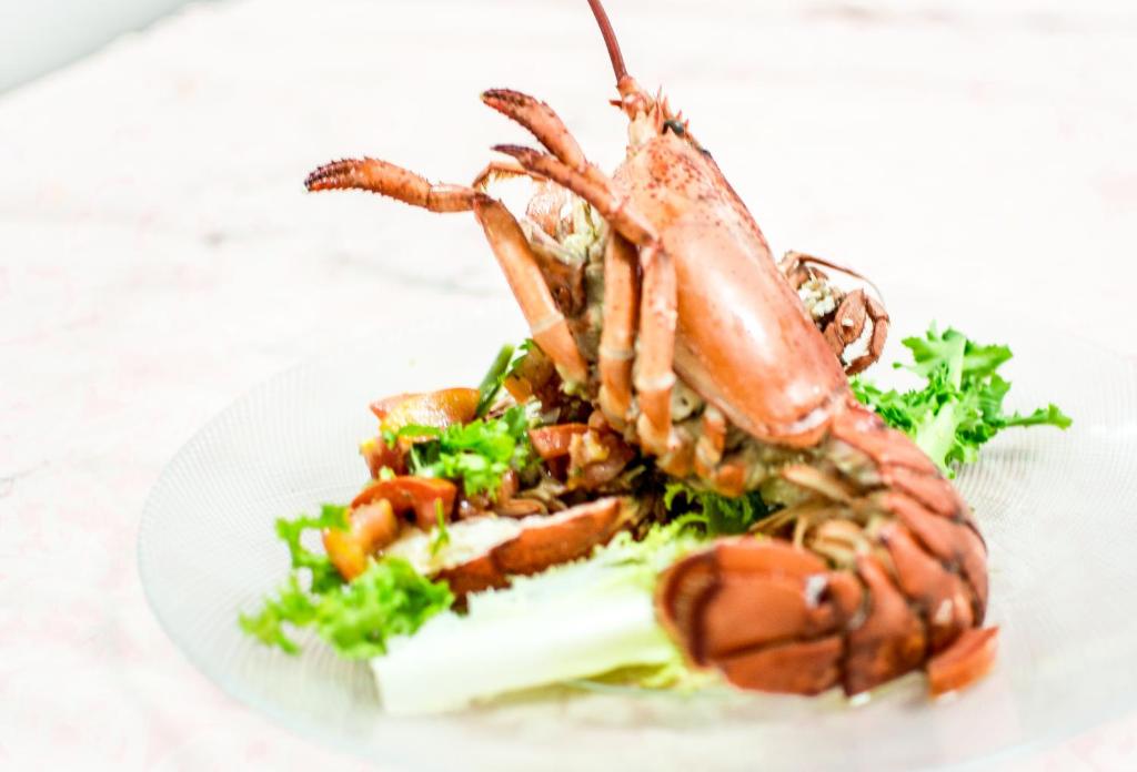 a lobster on a plate with a salad at Hotel Spartivento in Chia