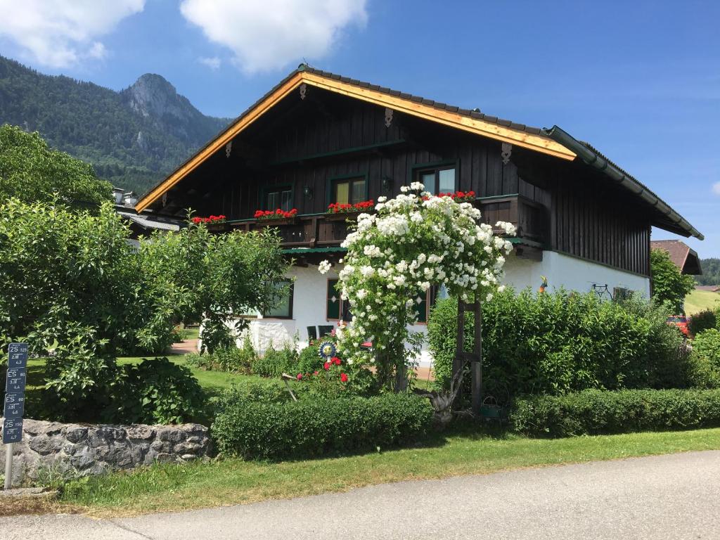 a black and white house with flowers in front of it at Ferienwohnung Meindl Elfi An der Drachenwand 44 in Mondsee