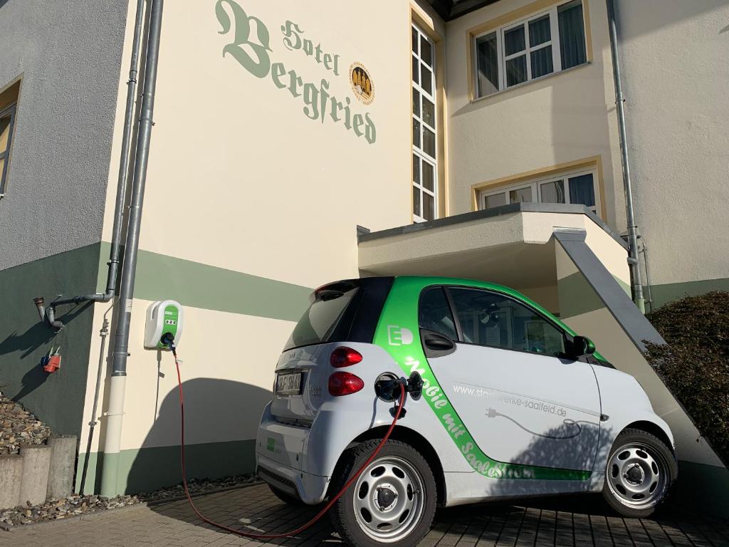 a small car is being charged in front of a building at Hotel & Restaurant Bergfried in Saalfeld