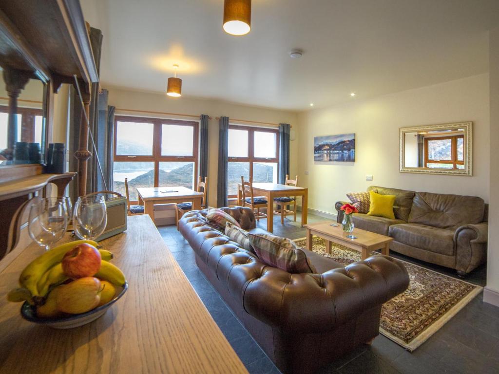 una sala de estar con sofá de cuero y un bol de fruta en Kirkaig Lodge, en Lochinver