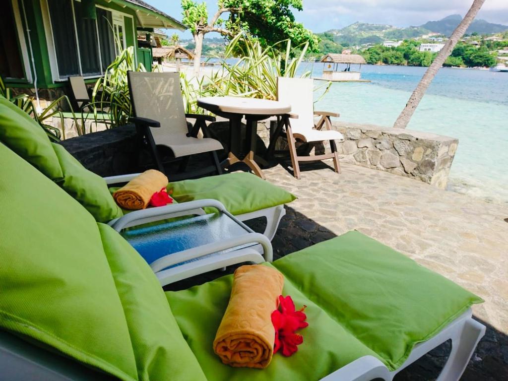 a group of green cushioned chairs sitting on a beach at Young Island Resort in Kingstown