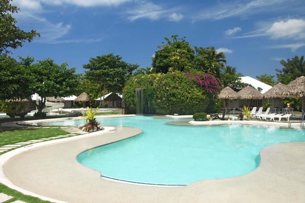 a large swimming pool with chairs and umbrellas at Almont Inland Resort in Butuan