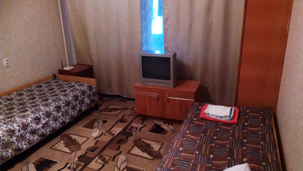 a hotel room with a bed and a tv and a floor with shoes at Готель. Квартири подобово in Yuzhnoukrainsk 
