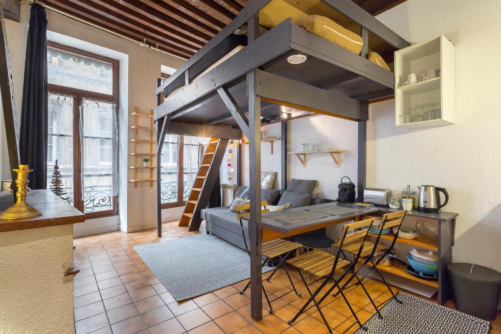 Cama elevada en habitación con mesa y sofá en La fenêtre Saint jean en Lyon