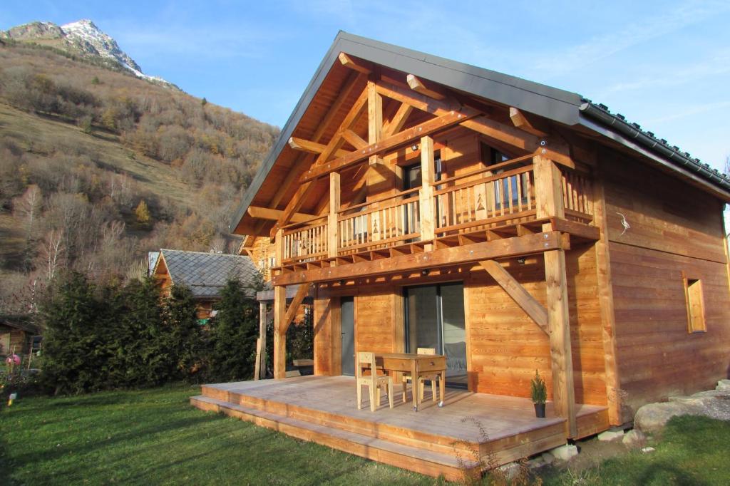 a log cabin with a deck and a table at Chalet de l'Oisans in Allemont