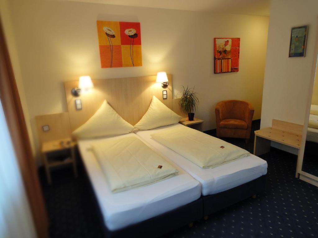 a hotel room with a large bed and a chair at Landgasthof Hock in Großostheim