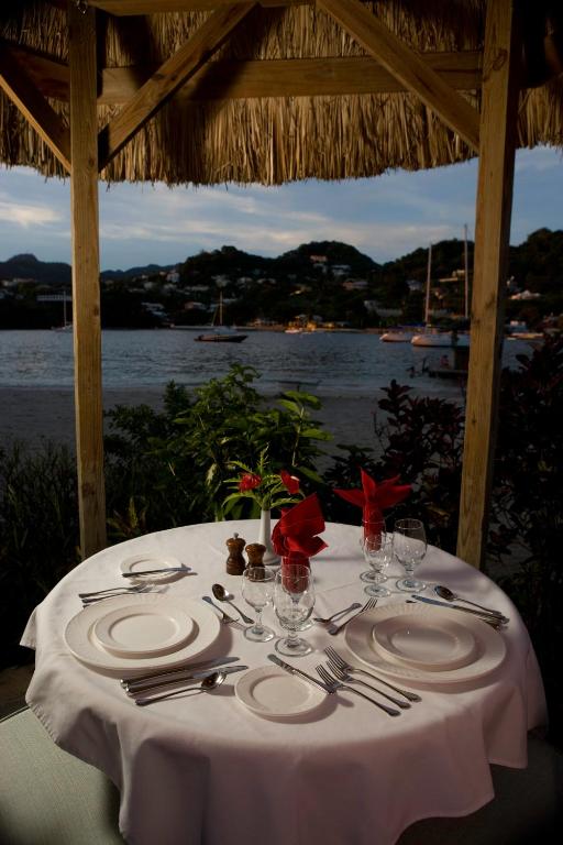 a table with plates and silverware and a view of the water at Young Island Resort in Kingstown