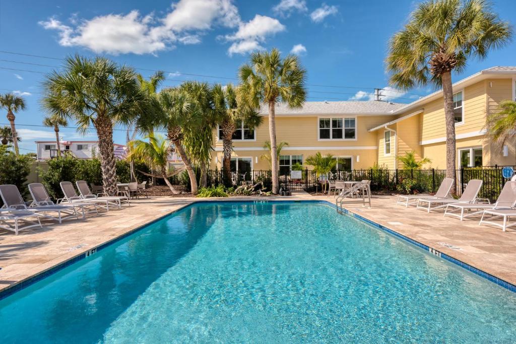 a pool with chairs and palm trees in front of a house at Escape Casey Key in Nokomis