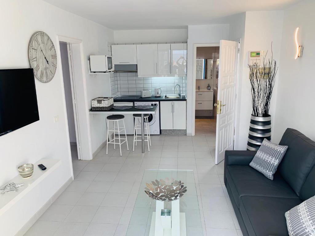 een woonkamer met een blauwe bank en een keuken bij Forever Views in Puerto del Carmen