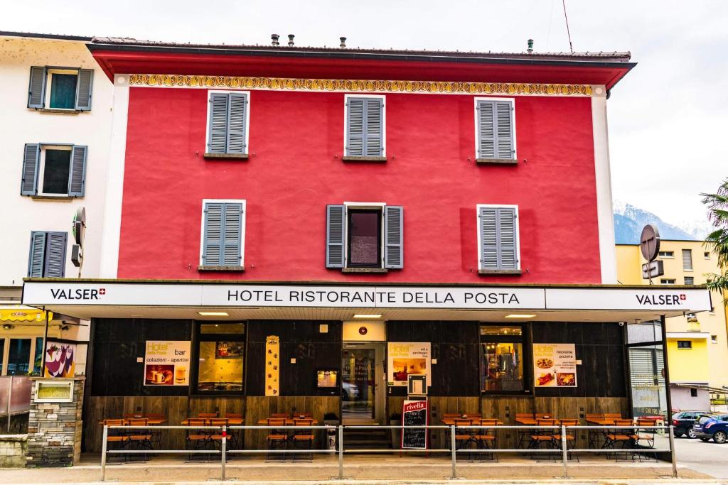 um edifício vermelho com um instituto hoteleiro bilayan pesta em Hotel della Posta em Biasca