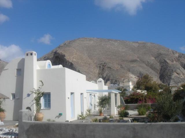 una casa blanca con una montaña en el fondo en Thera Incognita Studios, en Perissa