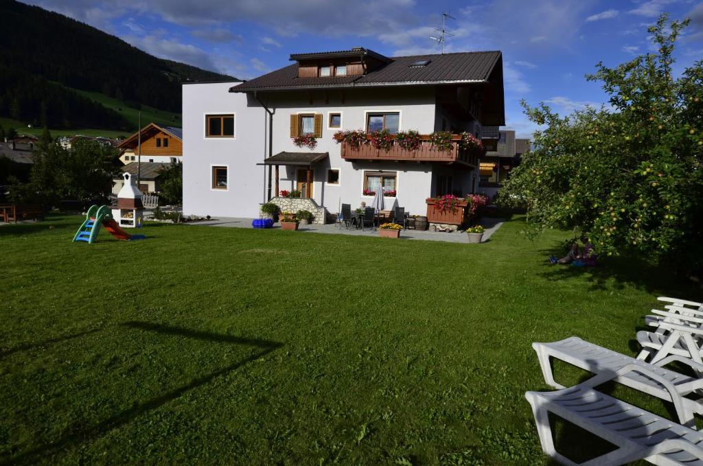 une maison blanche avec une cour dotée de chaises longues dans l'établissement Haus Cosso, à Villabassa