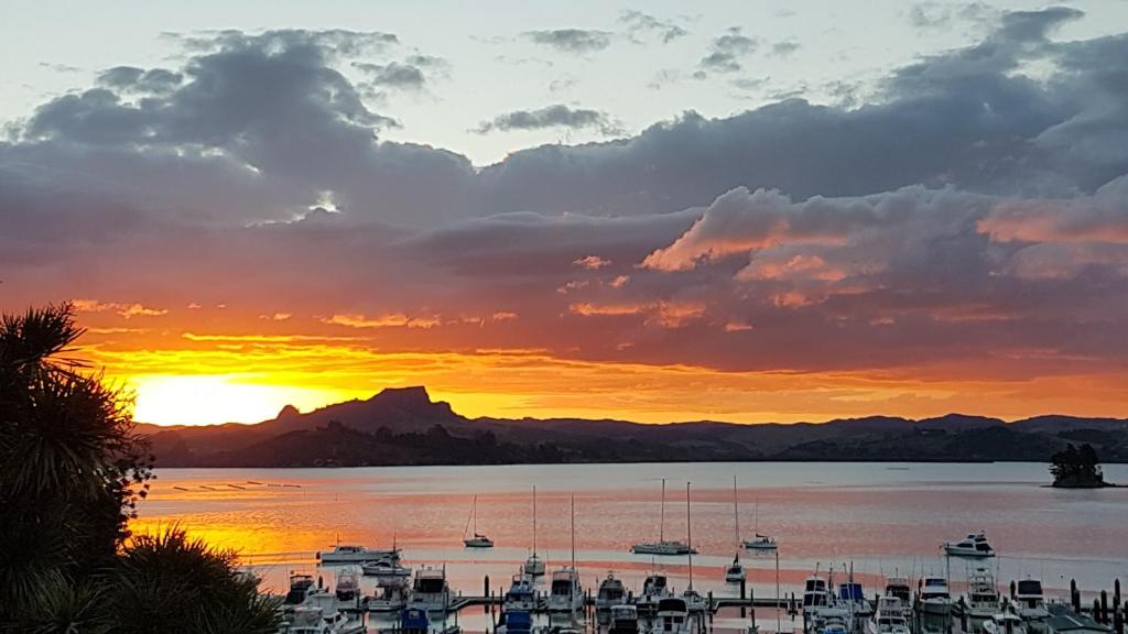 a sunset over a harbor with boats in the water at Whangaroa Lodge Motel in Whangaroa