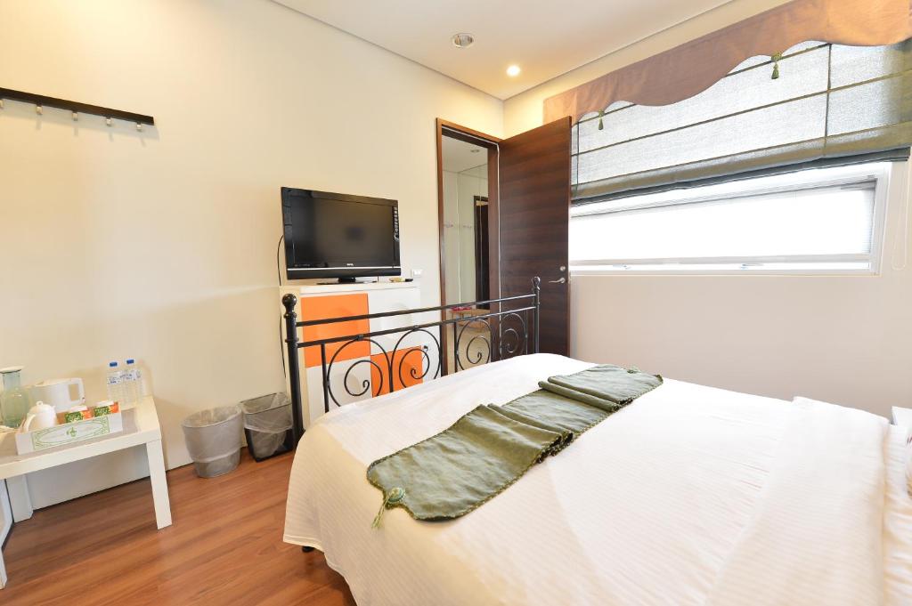 a bedroom with a bed and a flat screen tv at Penghu Chenhi Bay Homestay in Baisha
