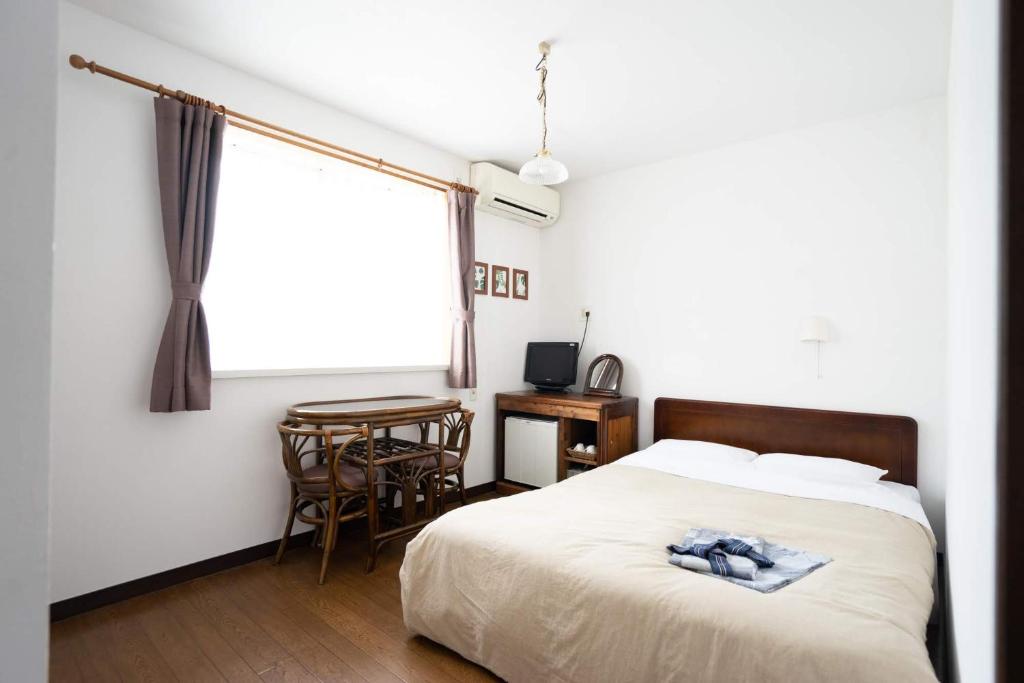 a bedroom with a bed and a table and a window at Beach Side Inn Shirahama in Shimoda