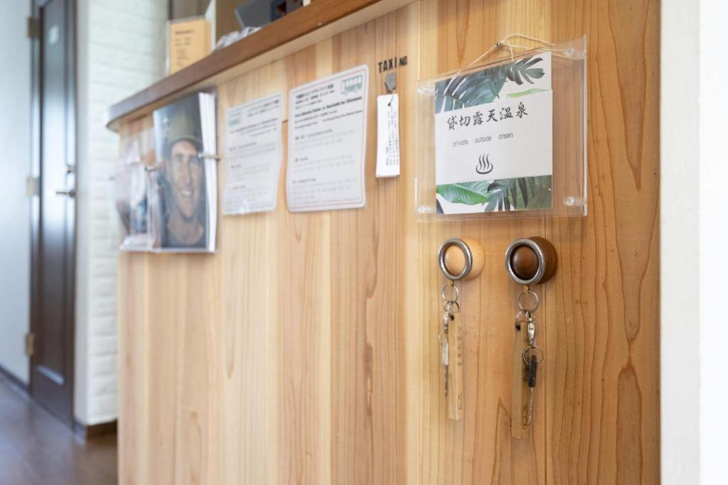 a wooden wall with certificates and scissors on it at Beach Side Inn Shirahama in Shimoda