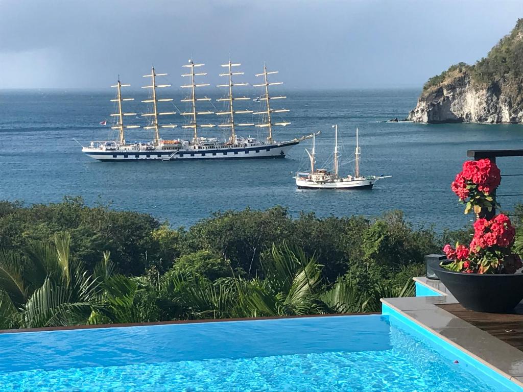 a swimming pool with two boats in the water at Villa Pelican Lodge in Deshaies