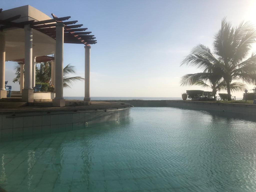 ein Pool vor einem Haus mit Palmen in der Unterkunft Almasi Oceanfront Nyali in Mombasa