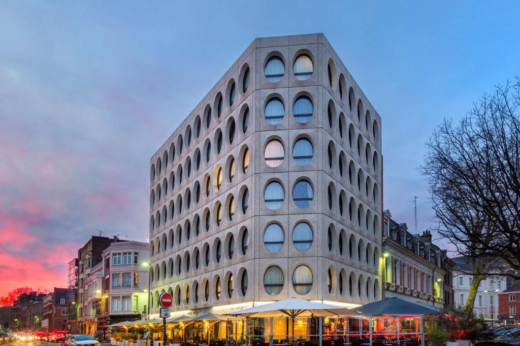 Un alto edificio bianco in una strada di città di notte di Best Western Premier Why Hotel a Lille