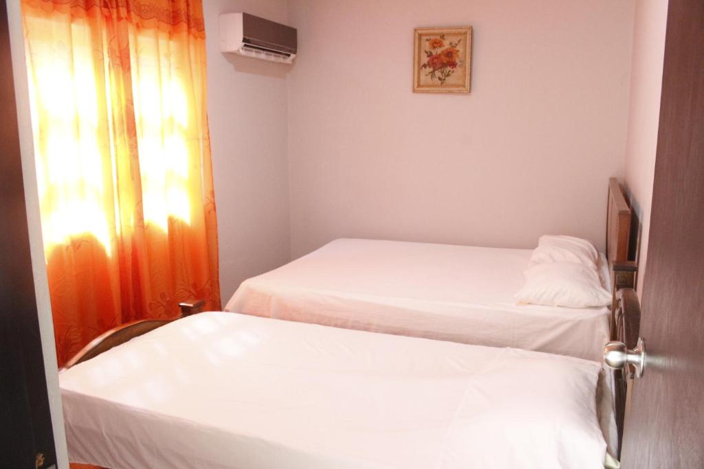 two beds in a small room with a window at Apartamentos Arpushana in Ríohacha