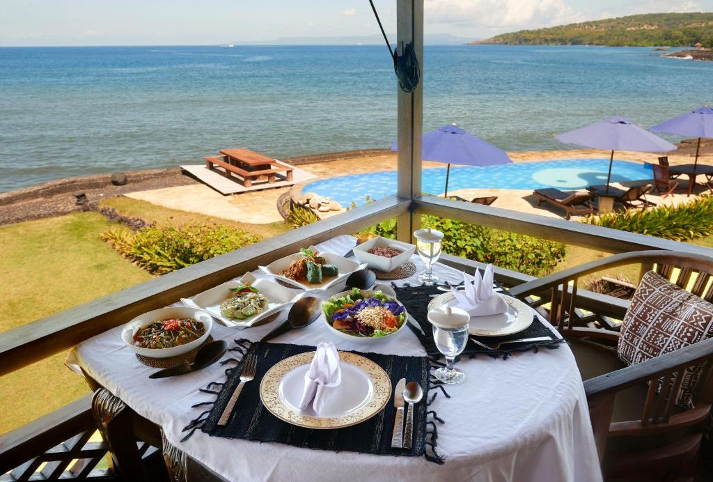 einen Tisch mit Teller mit Speisen auf einem Balkon mit Meerblick in der Unterkunft Jasri Bay Hideaway in Jasri