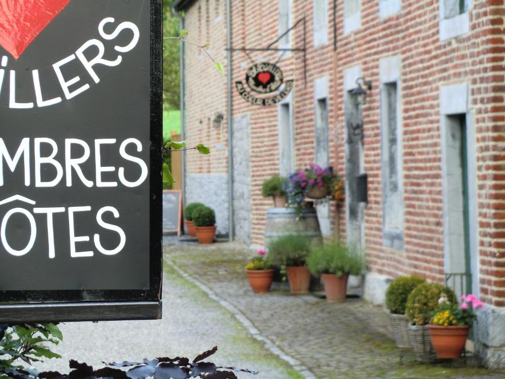 um sinal em frente a um edifício de tijolos com vasos de plantas em B&B Au Coeur de Villers em Villers-Sainte-Gertrude
