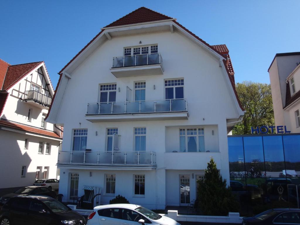 ein weißes Gebäude mit Balkon darüber in der Unterkunft Residenz am Strande in Warnemünde