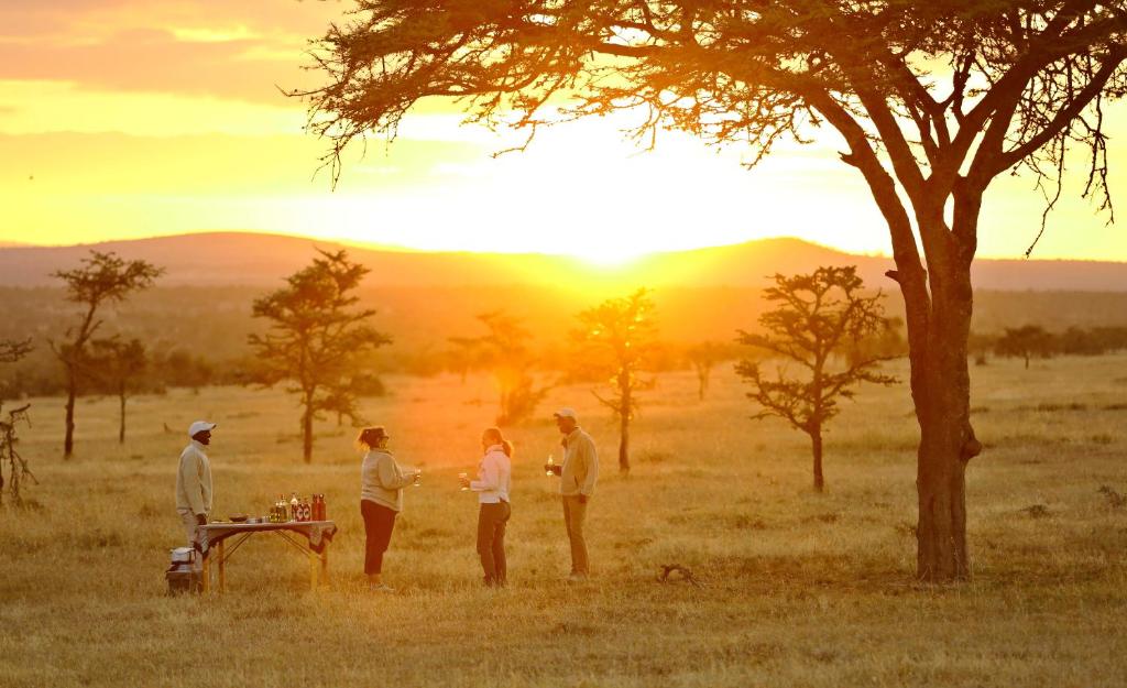 a group of people standing in a field with the sunset at Kicheche Laikipia Camp in Ol Pejeta Conservancy