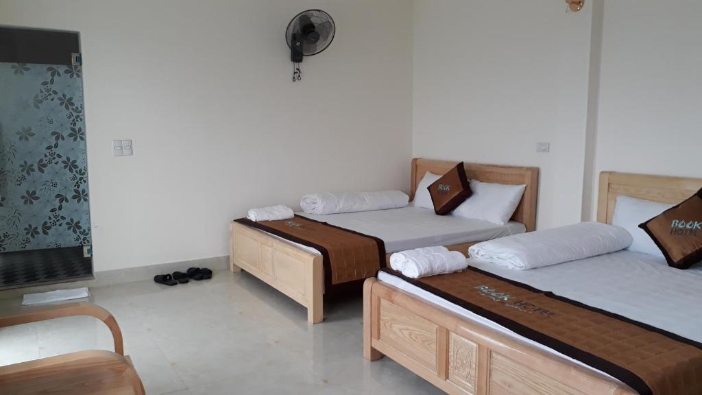 um quarto com duas camas e uma tv nele em Nhà nghỉ Book em Hoàn Giáp
