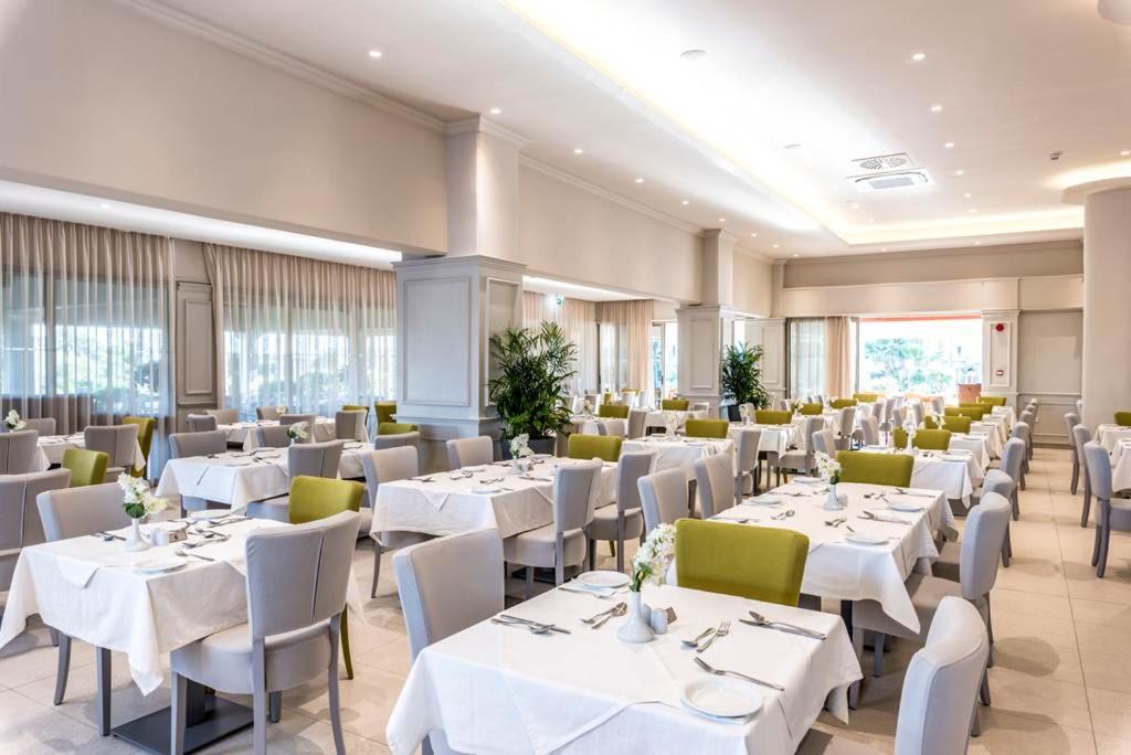 a dining room with white tables and chairs at Nissiana Hotel & Bungalows in Ayia Napa