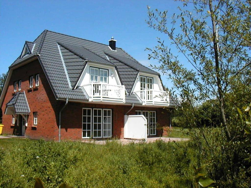 a red brick house with a gambrel roof at Gaestehaeuser-Heidehof-Wohnung-4 in Süderhöft